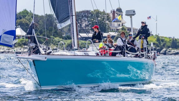 People sailing on a turquoise sailboat.