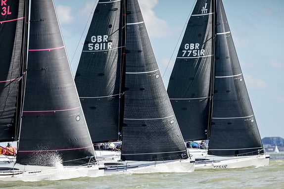 Sailboats racing with black sails on water.