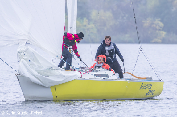 Three people sailing a yellow boat.
