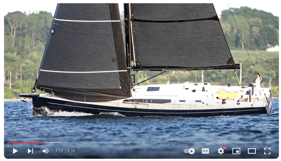 Sailboat with black sails on water.