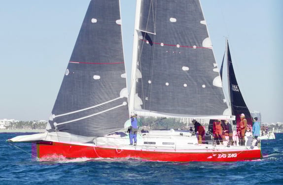 Red sailboat with crew on open water.