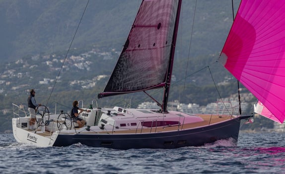 Sailboat with pink sail on the water.