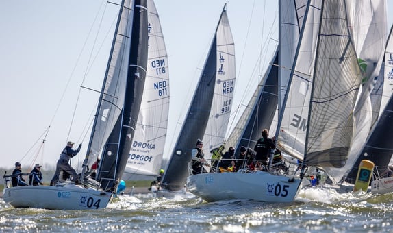 Sailboats racing on a sunny day with crews managing sails.