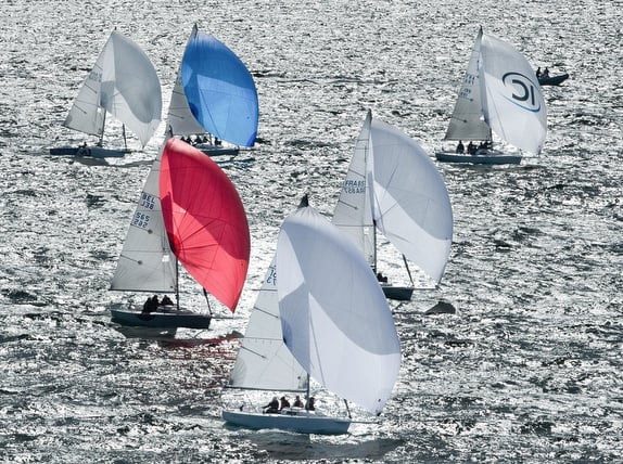 Sailboats with colorful sails on shimmering water.