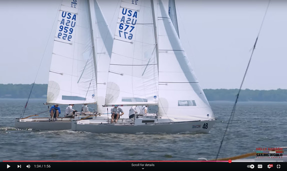 Two sailboats racing on open water with clear skies.