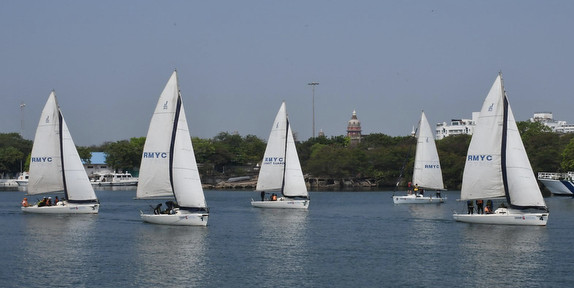 Sailboats on a calm lake under blue sky.
