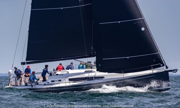 Sailboat racing with crew on the ocean.