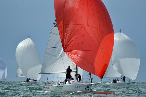 Sailboats racing with colorful spinnakers on water.
