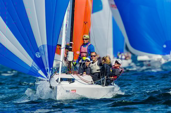 Group sailing on a boat with colorful sails on a sunny day.