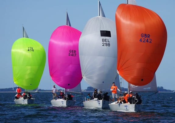 Colorful sailboats racing on open water.