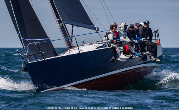 Sailboat with crew racing on open water.
