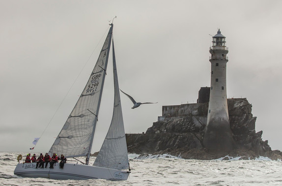 Sailboat near lighthouse on a cloudy day.