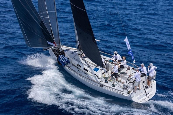 Sailboat with crew navigating on open water.