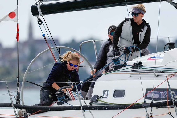 Three sailors working on a sailboat.