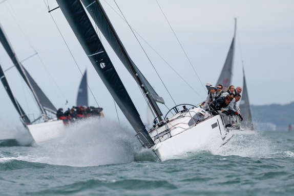 Sailboats racing on choppy waters with crew leaning over the side.