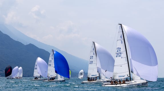 Sailboats racing on a lake, mountainous backdrop.