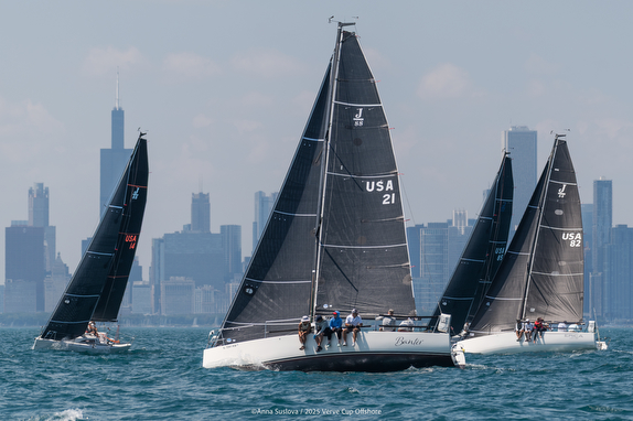 Sailboats racing with city skyline backdrop.
