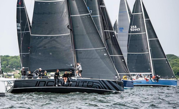 Sailboats racing with black sails on water.