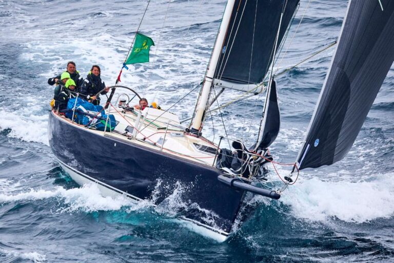 Sailboat navigating choppy waters with crew handling the sails.