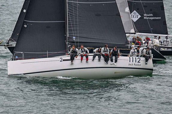 Sailboat racing with crew sitting on side.
