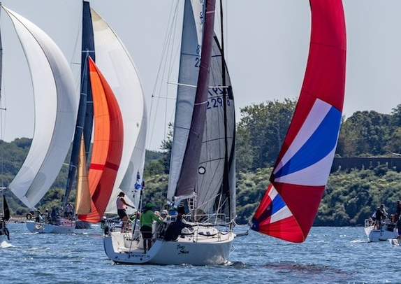 Sailboats racing with colorful spinnakers on water.