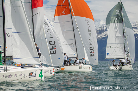 Sailboats racing closely on a sunny day with colorful sails.