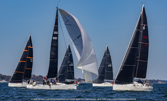 Sailboats racing on a sunny day with full sails catching the wind.