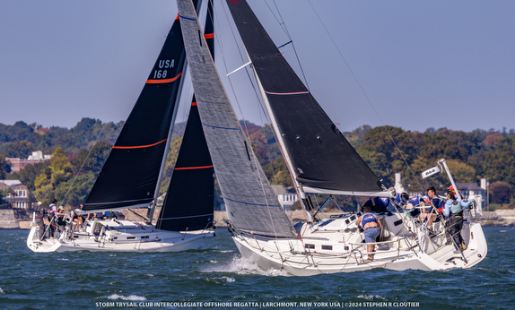 Sailboats racing on a sunny, windy day with crew adjusting sails.