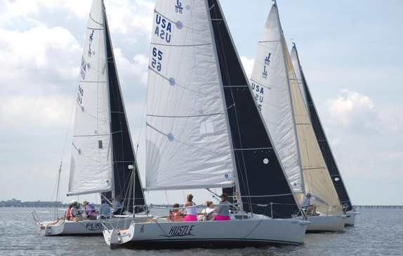 Sailboats racing on a calm water body with sails fully raised.