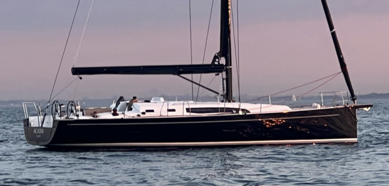 Sailboat on calm ocean at sunset.