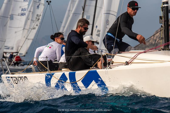 A group of sailors navigating a sailboat on choppy waters.