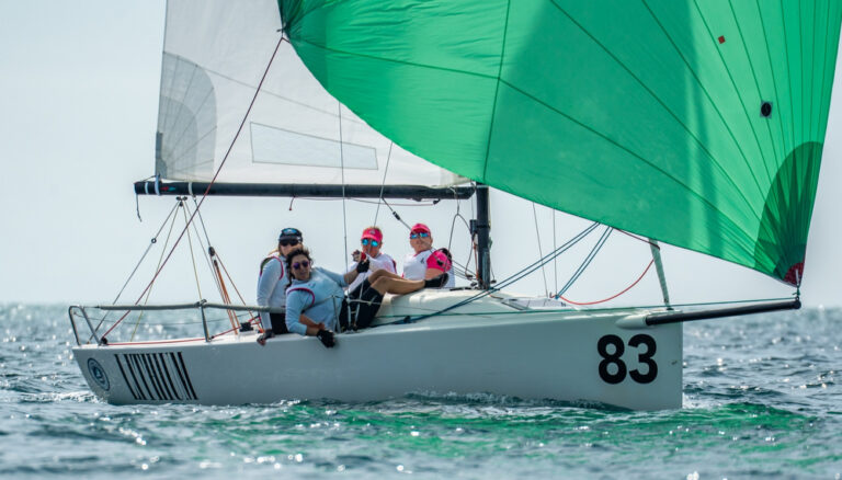 Racing sailboat with green spinnaker and crew