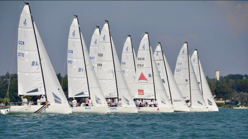 Row of white sailboats racing on blue water
